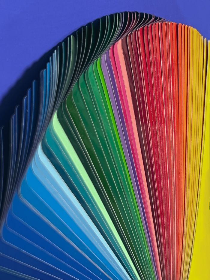 A colorful fan of vibrant color samples in a rainbow spectrum on a blue background.